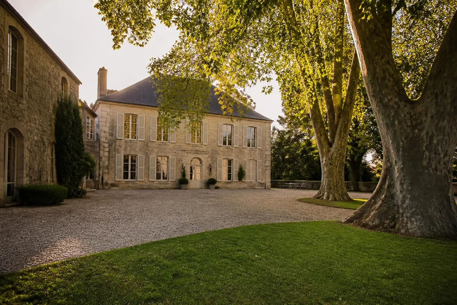 Manoir en pierre et sa cour gravillonnée, en fin de journée